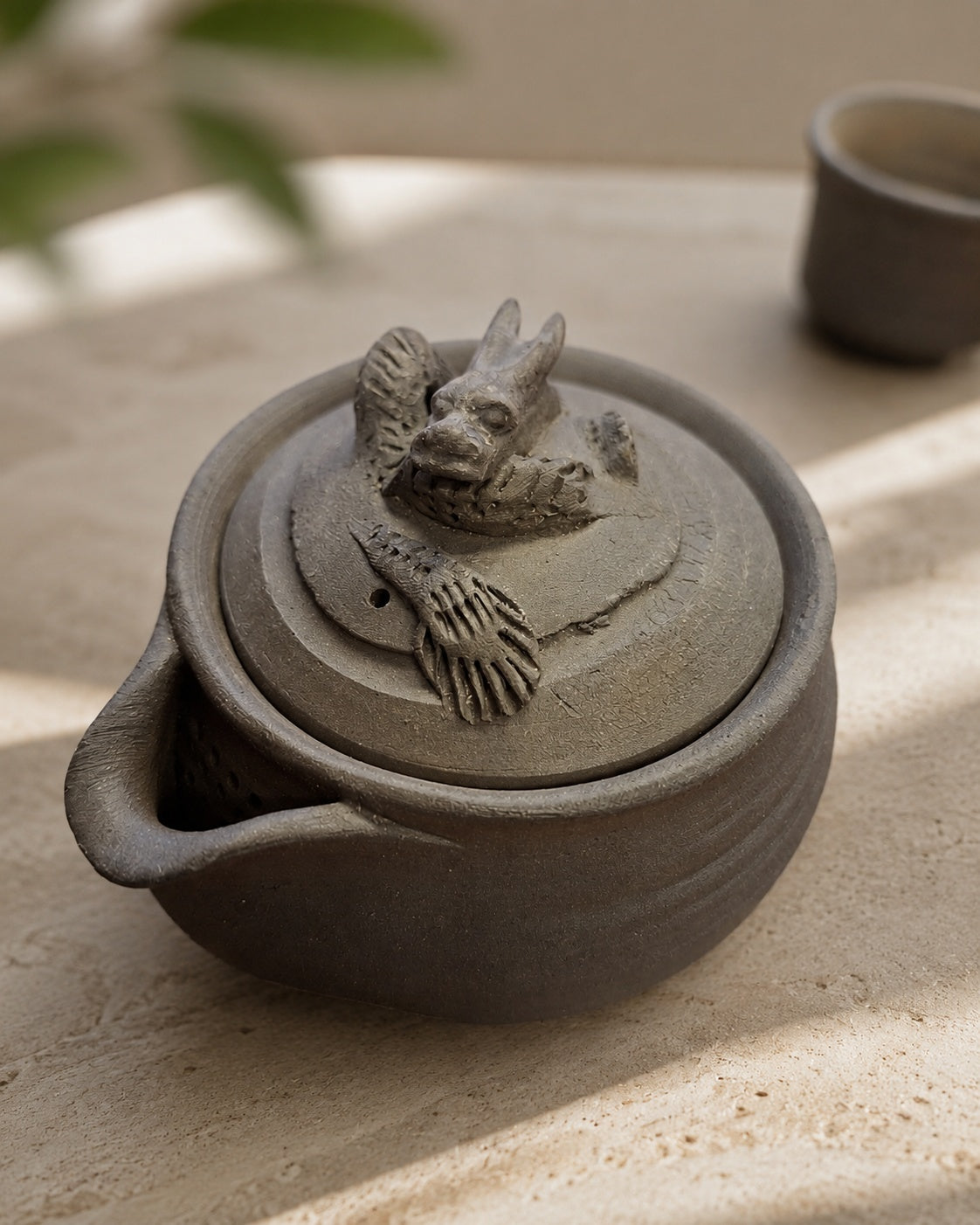 Angled view of the hōhin, dragon finial lit from the right, pour lip left.